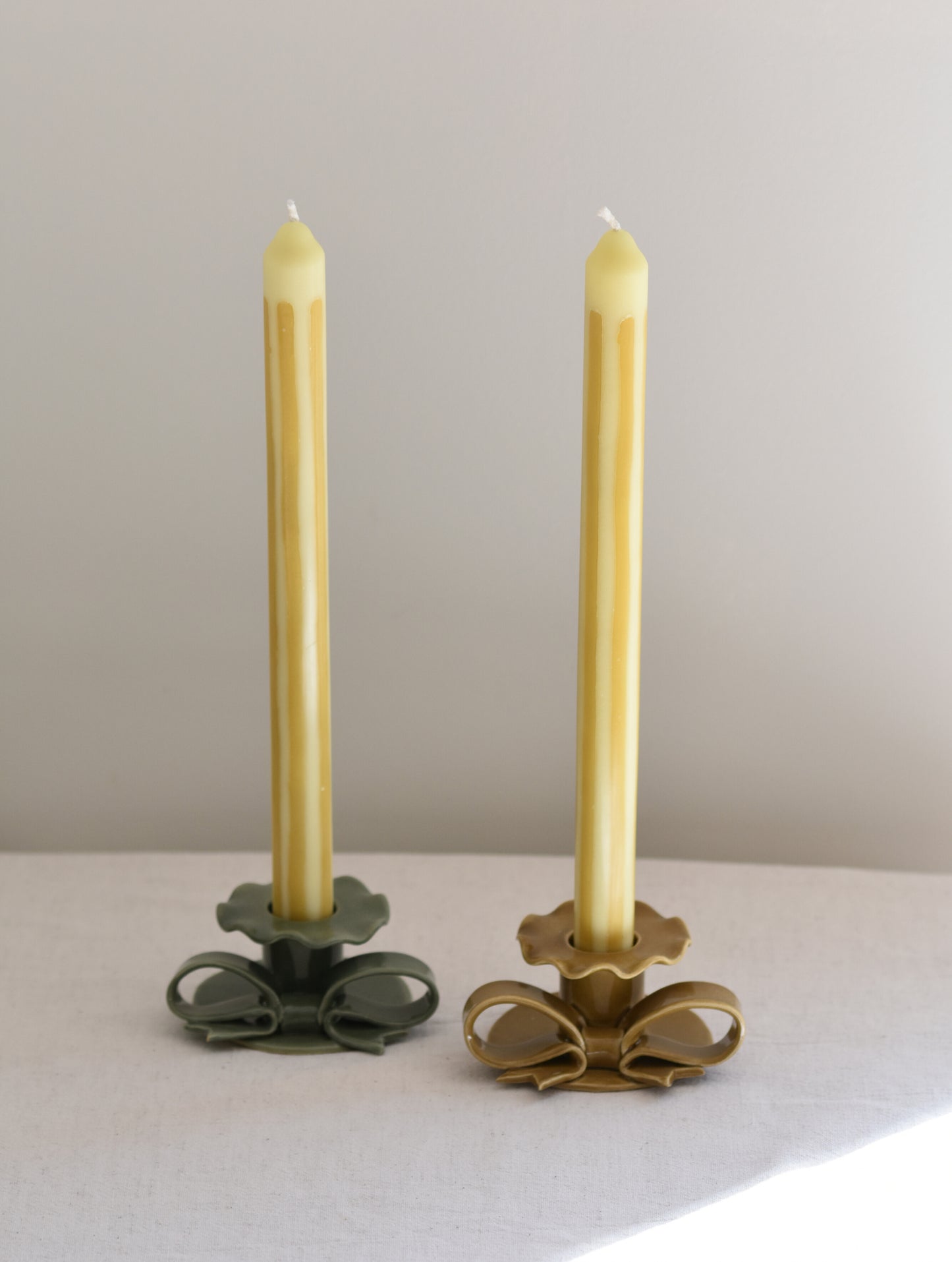 A pair of two Pygmalion London Butter Boy dinner candles with striped design in mustard and butter yellow.