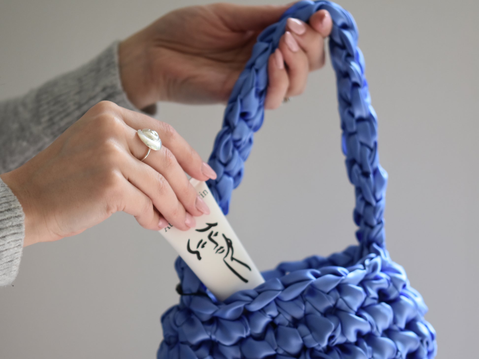 Austin Austin Organic Palmarosa & Vetiver hand cream tube with face outline artwork by Christian Newby, coming out of a blue Isla de Gar Hive bag.