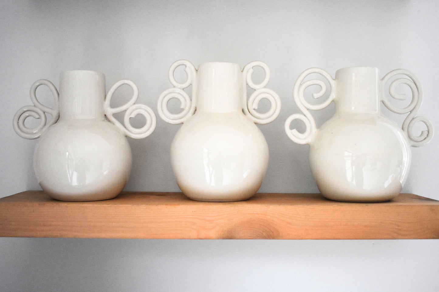 We Are Clay Butterfly Wing Vase, Celtic Spiral Vase and Curly Sue Vase in white ceramic with spiral handles.