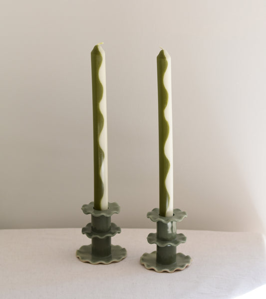 A pair of two Pygmalion London Botanist dinner candles with wave design in dark olive and off-white.