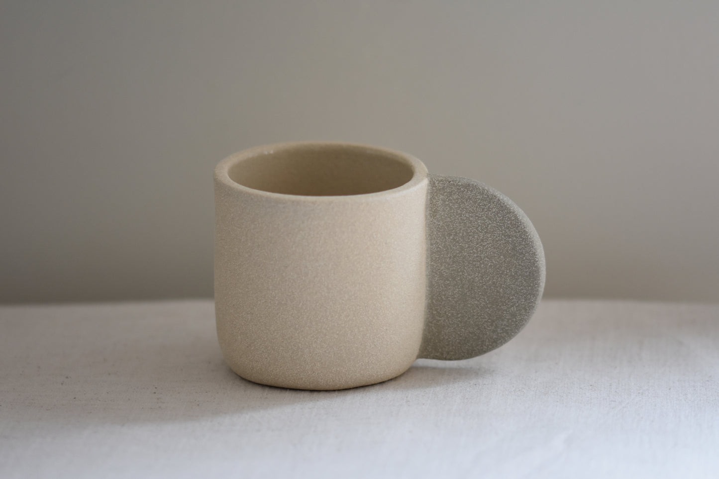Brutes ceramics stoneware medium signature mug in sand with grey handle and textured finish.