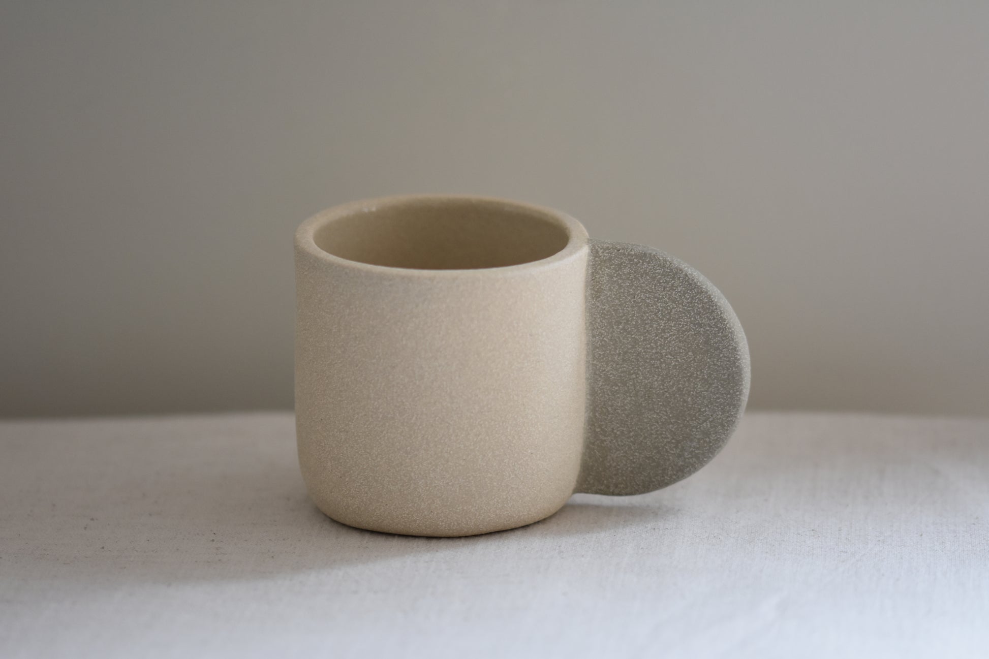 Brutes ceramics stoneware medium signature mug in sand with grey handle and textured finish.