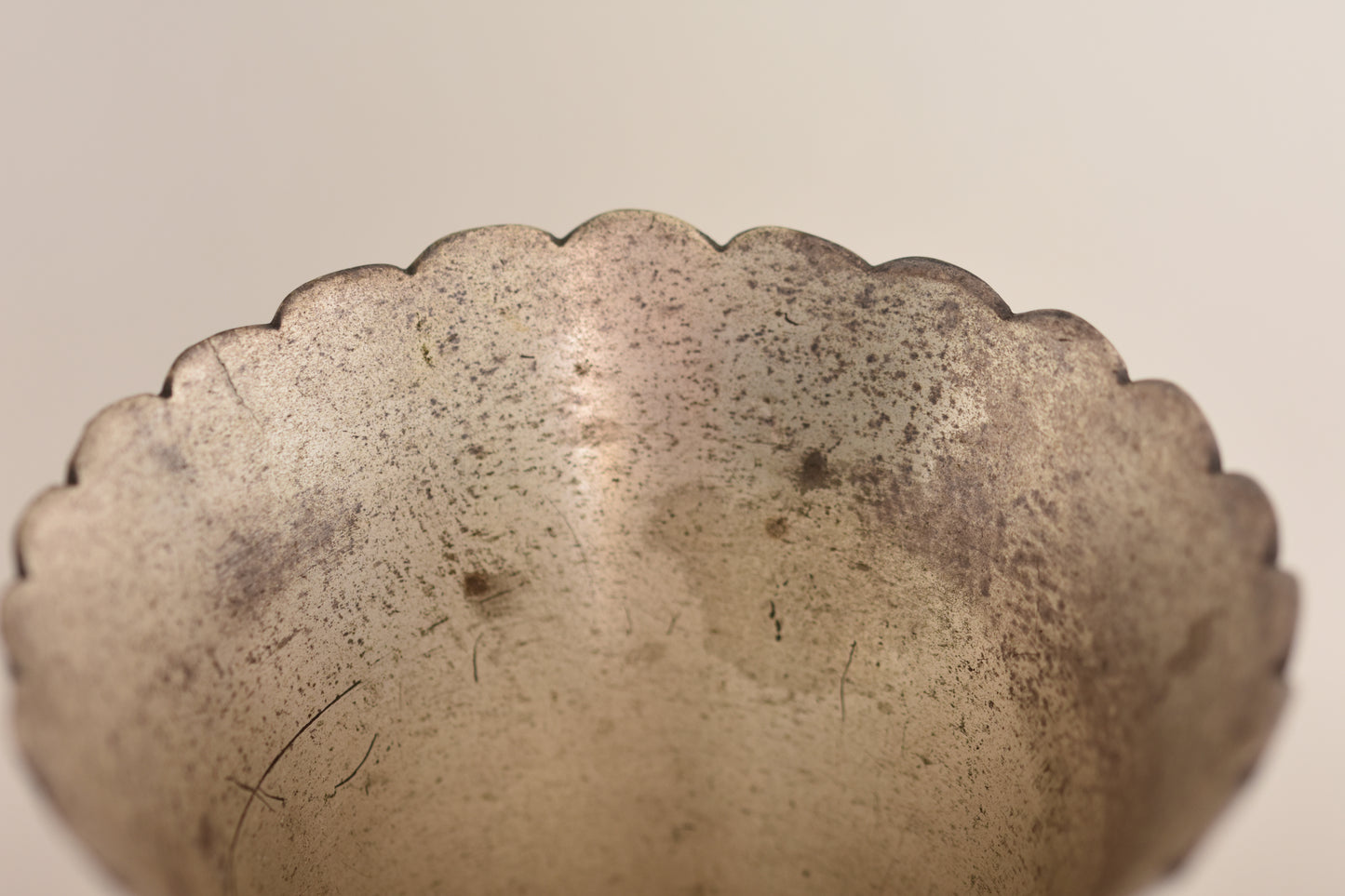 Close up of a vintage silver plated fluted vase on a beige background.