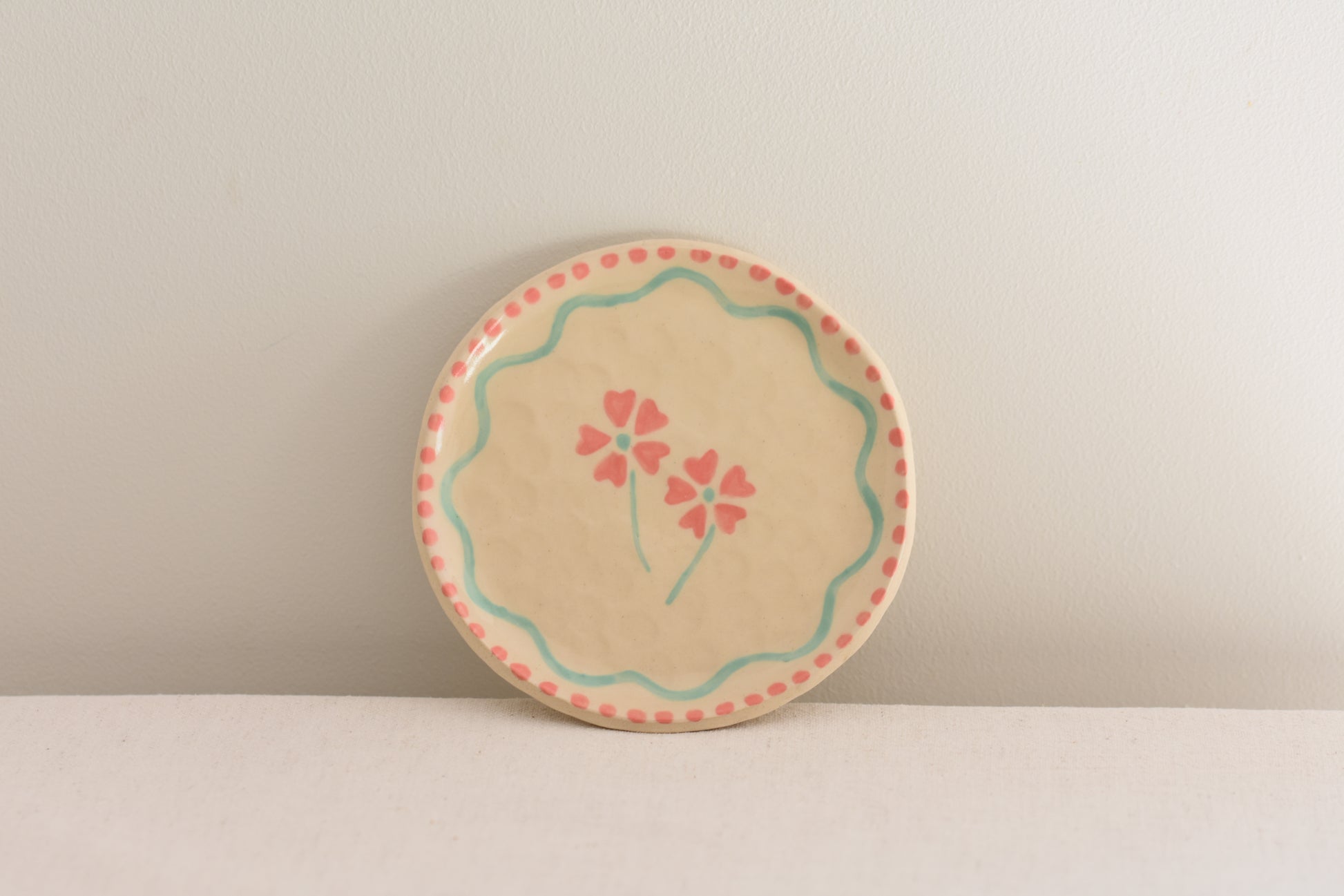 Blume Ceramics white stoneware small plate with hand painted floral design in pink and light green.
