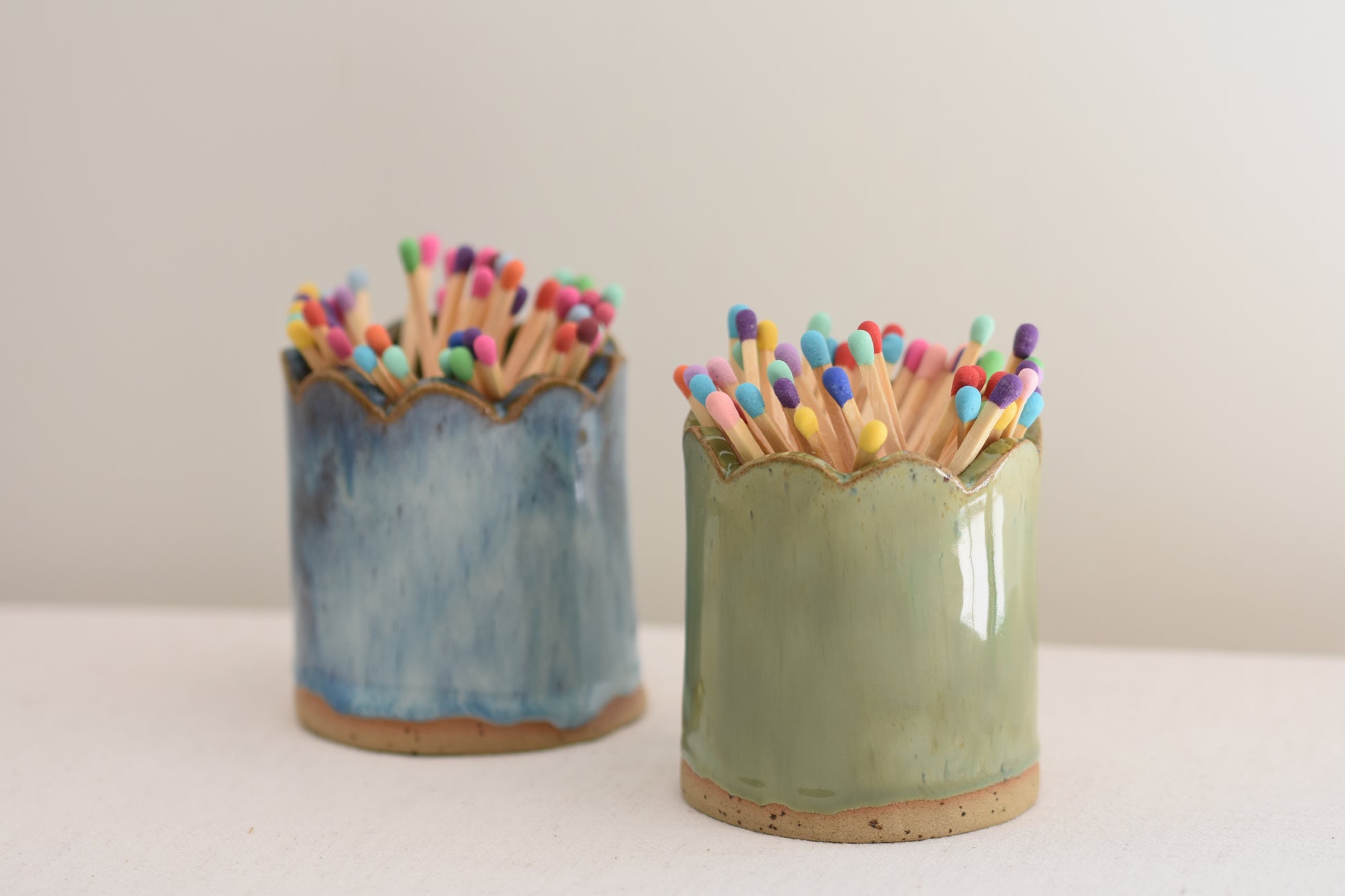 Blume Ceramics stoneware matchstick holders, glazed in green and blue, with scalloped tops and multicolour matches.