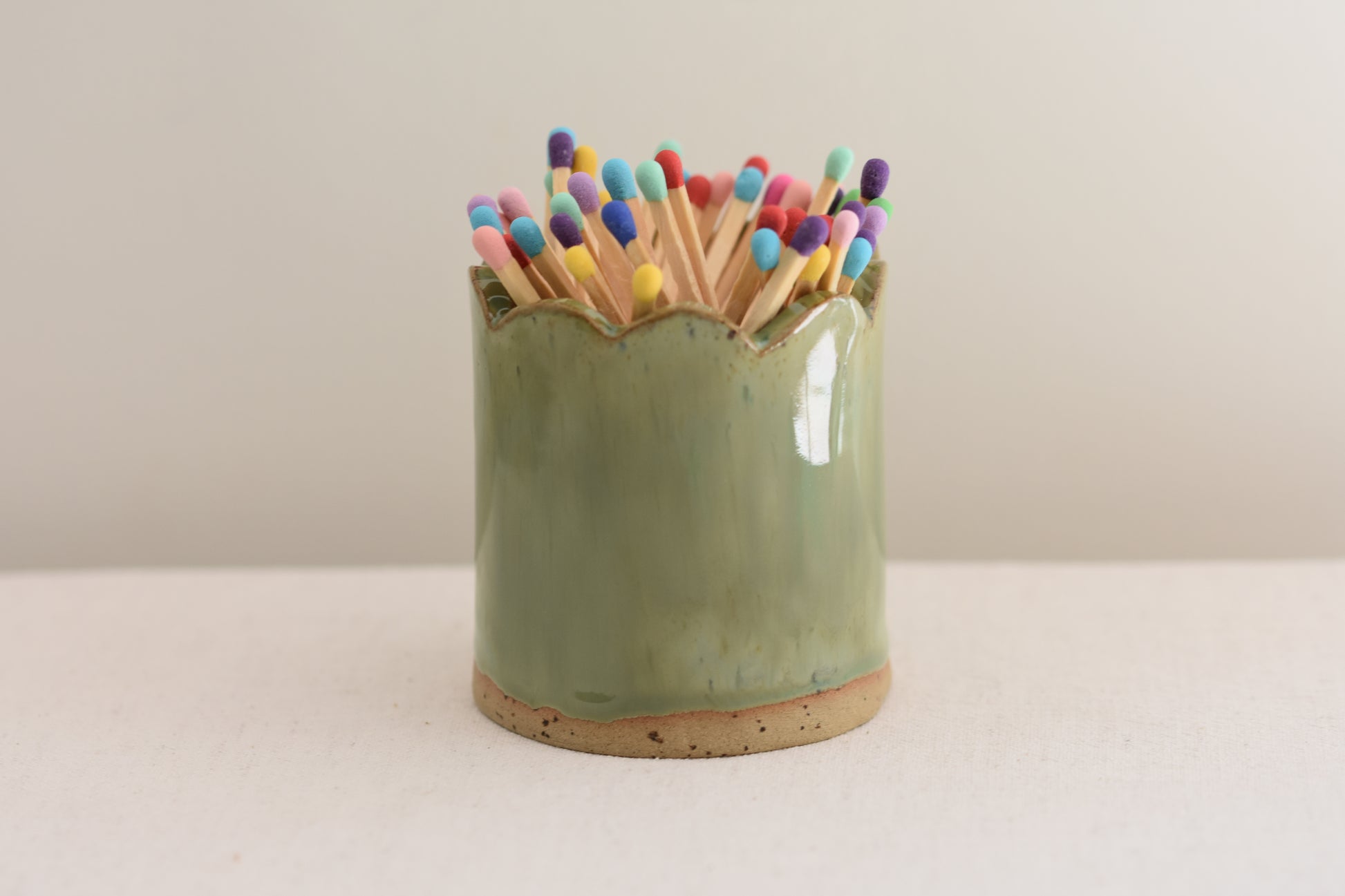 Blume Ceramics stoneware matchstick holder, glazed in green, with scalloped top and multicolour matches.