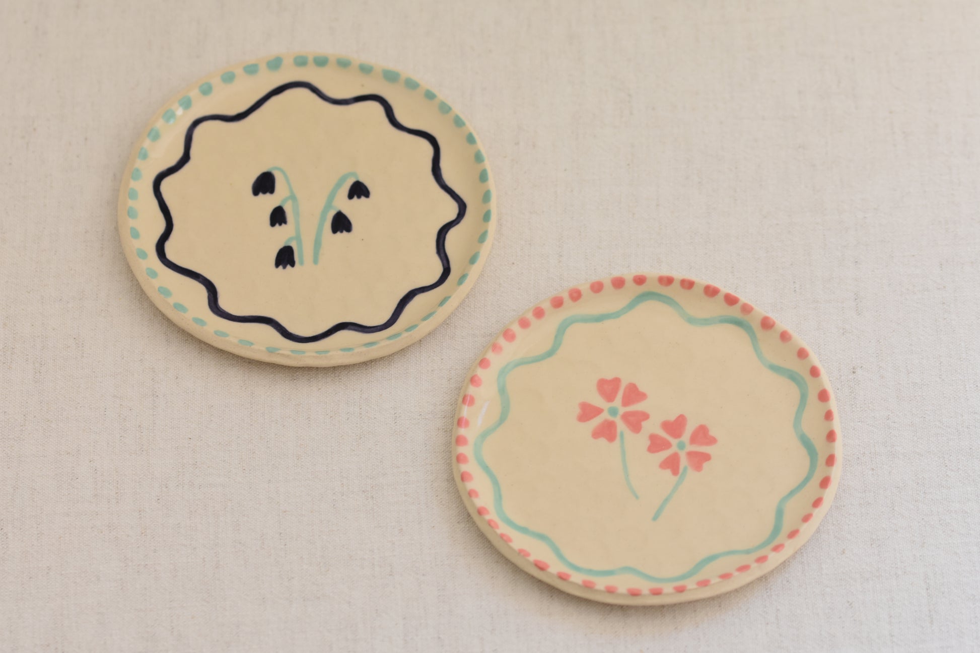 Blume Ceramics white stoneware small plates with hand painted floral design in pink and light green, and bluebell design in navy and light green.