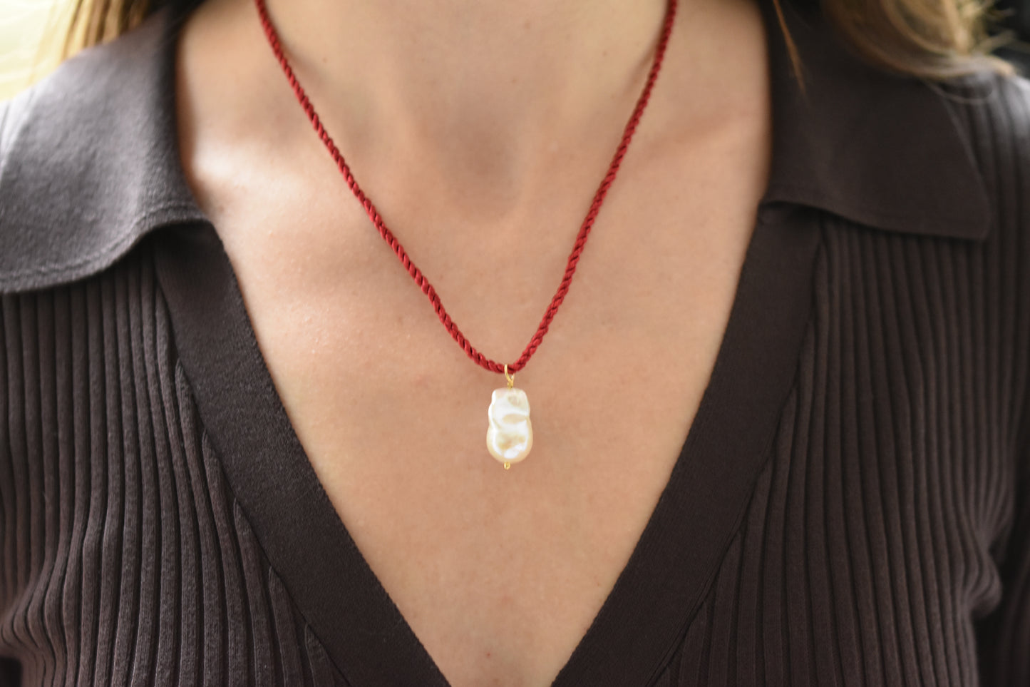 Sandralexandra baroque pearl on dark red silk twisted cord necklace, worn by a person.