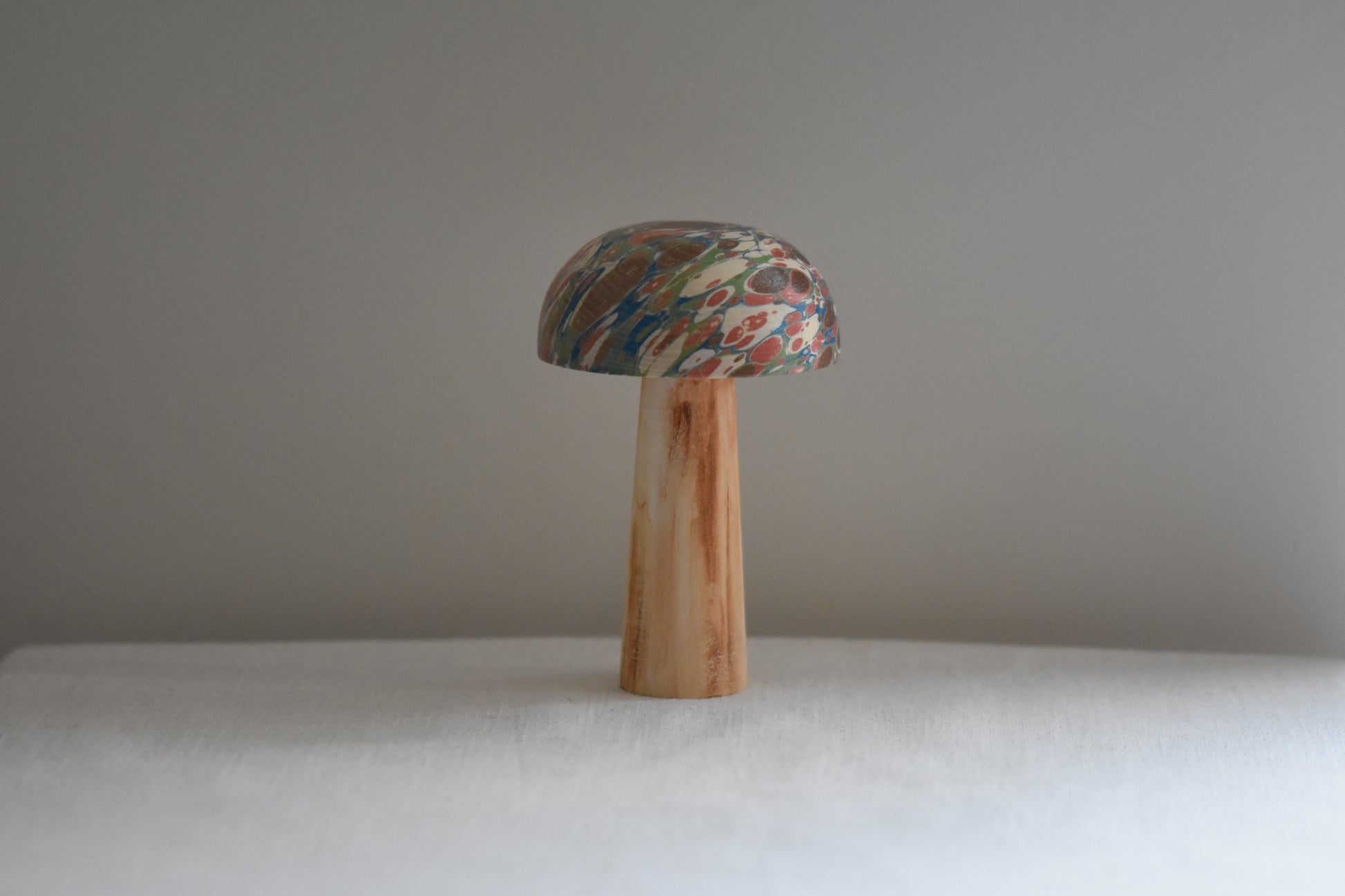 Jemma Lewis marbled wooden decorative toadstool on a beige background.