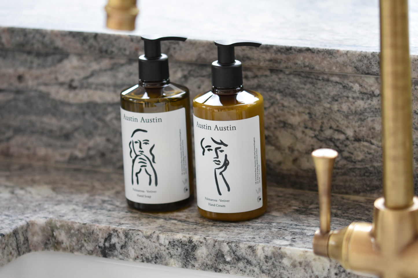 Austin Austin Organic palmarosa and vetiver hand cream and hand soap with face outline artwork by Christian Newby, by a kitchen sink.