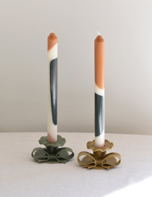 A pair of two Pygmalion London Munro dinner candles with colour block design in copper, dark emerald and pale pink.