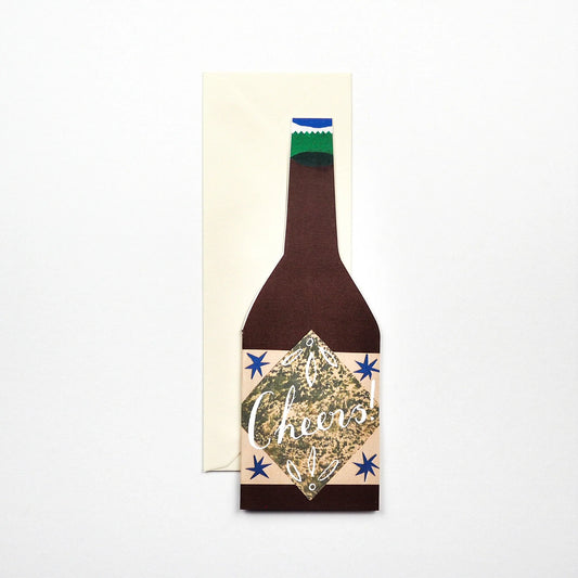 Hadley Paper Goods Cheers bottle shaped card in brown with blue stars, with an ivory envelope on a white background.