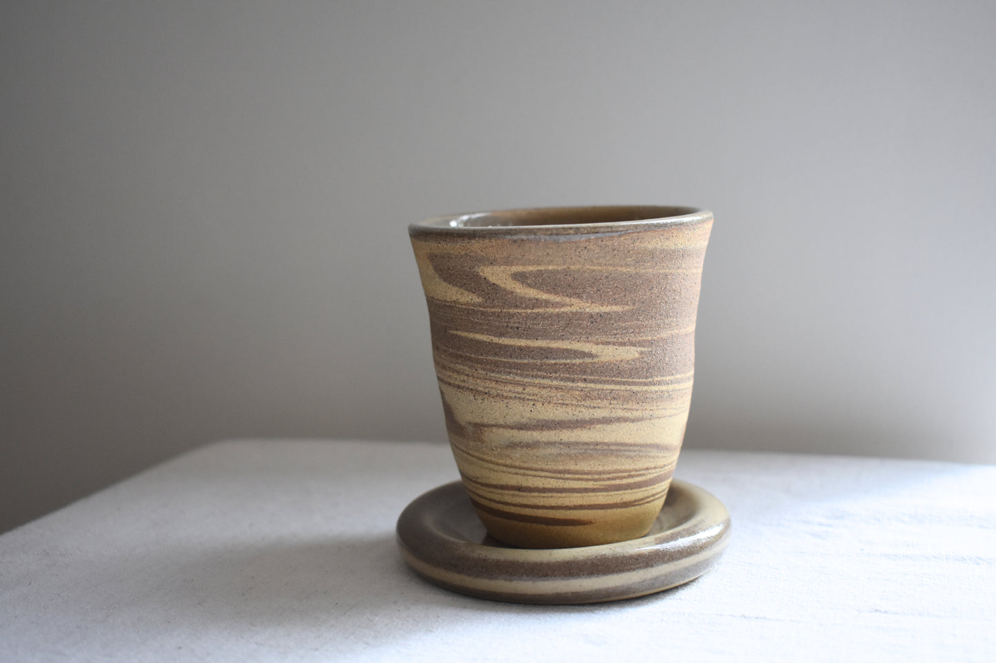 Ceramics by Sunny stoneware spiral cup on doughnut plate coaster with brown and beige marble pattern.