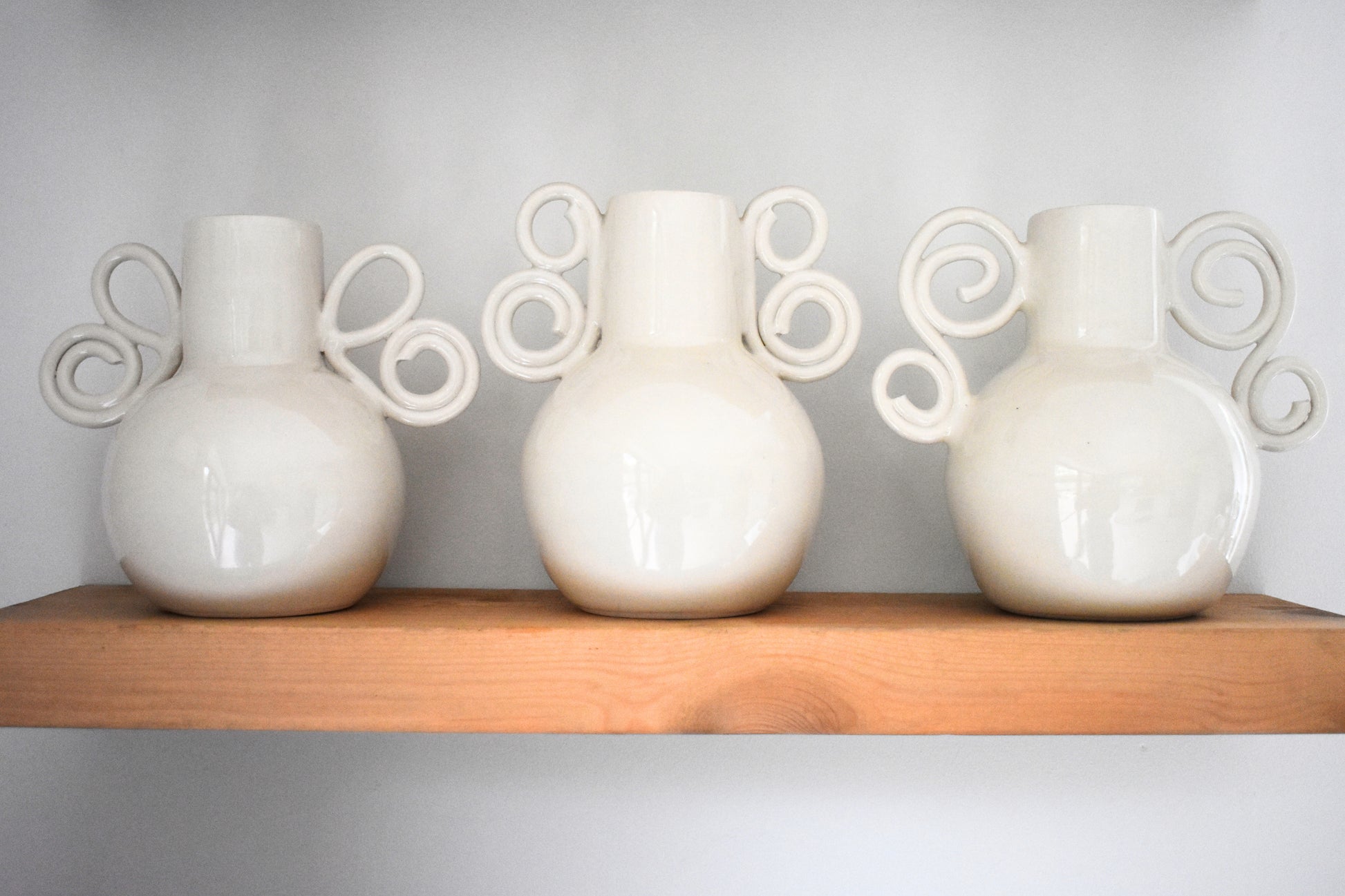 We Are Clay Butterfly Wing Vase, Celtic Spiral Vase and Curly Sue Vase in white ceramic with spiral handles.