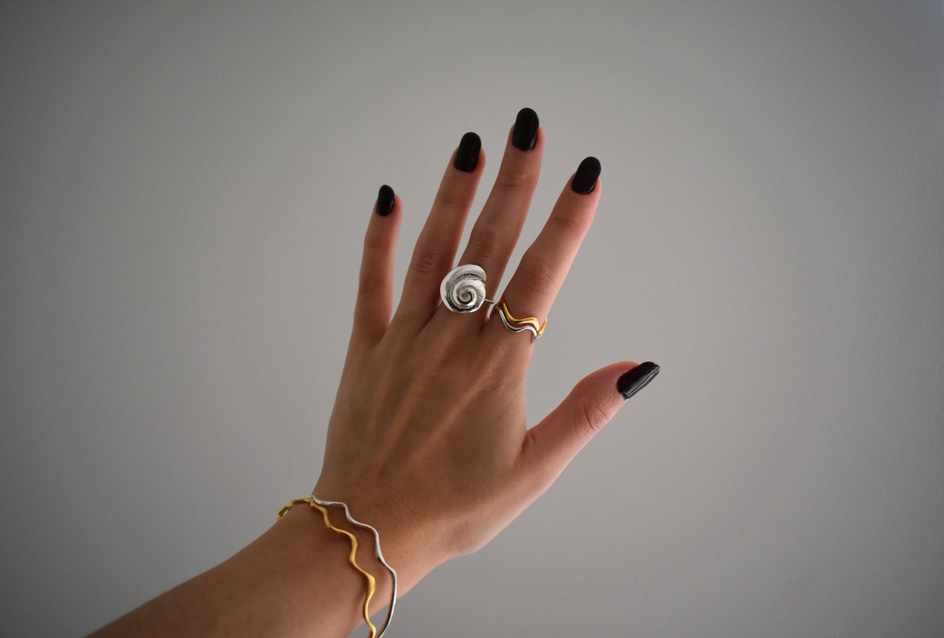 Hannah Bourn Periwinkle spiral swirl shell ring in silver with wavy Saccostrea rings and bangles in gold and silver.