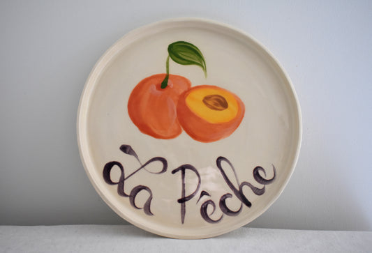 Harlie Brown earthenware ceramic La Peche plate with painted peach design and french writing.