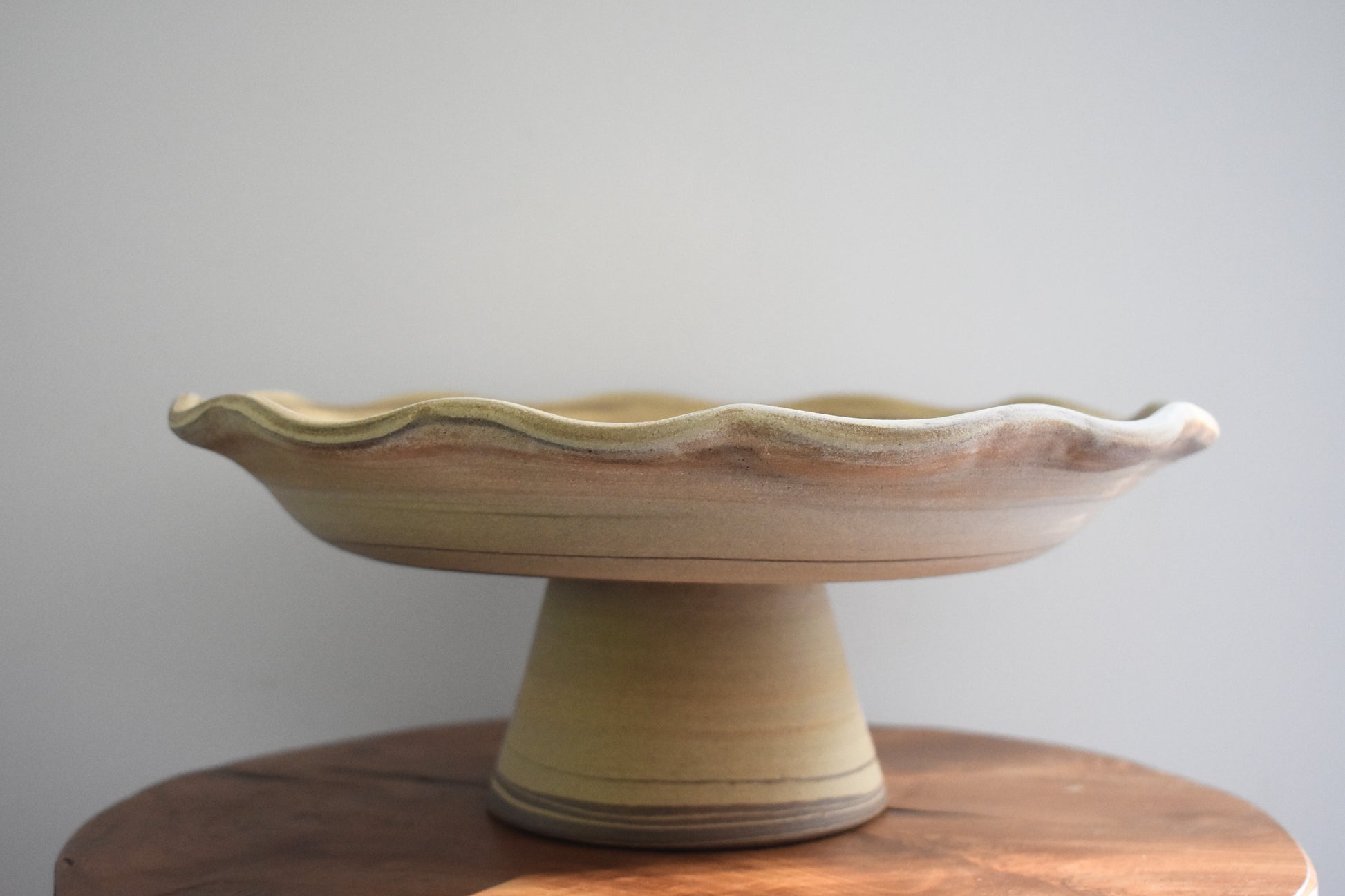 Ceramics by Sunny stoneware wavy frilled edge pedestal fruit bowl with brown and beige marble pattern.