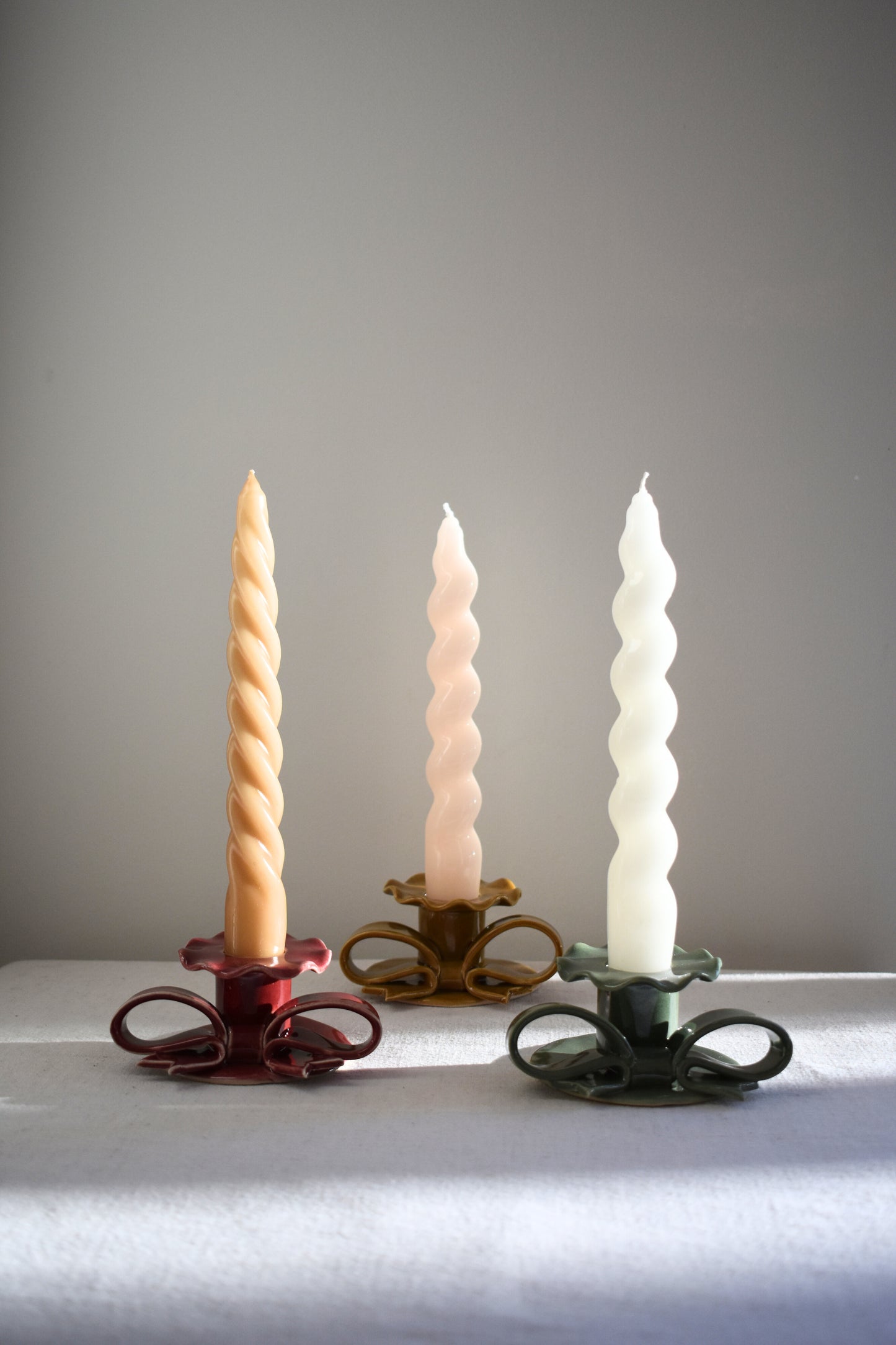 Superfluities stoneware ceramic Bow Candlesticks with frills in burgundy, honey ochre and green.