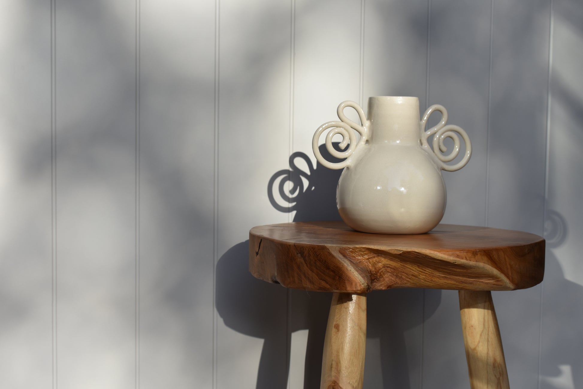 We Are Clay Pretzel Vase in white ceramic with spiral handles and it's shadow.