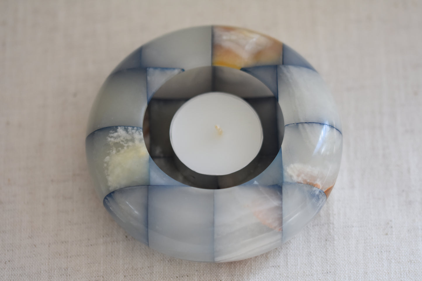 Vintage checkered onyx blue and brown tealight holder on a beige background.