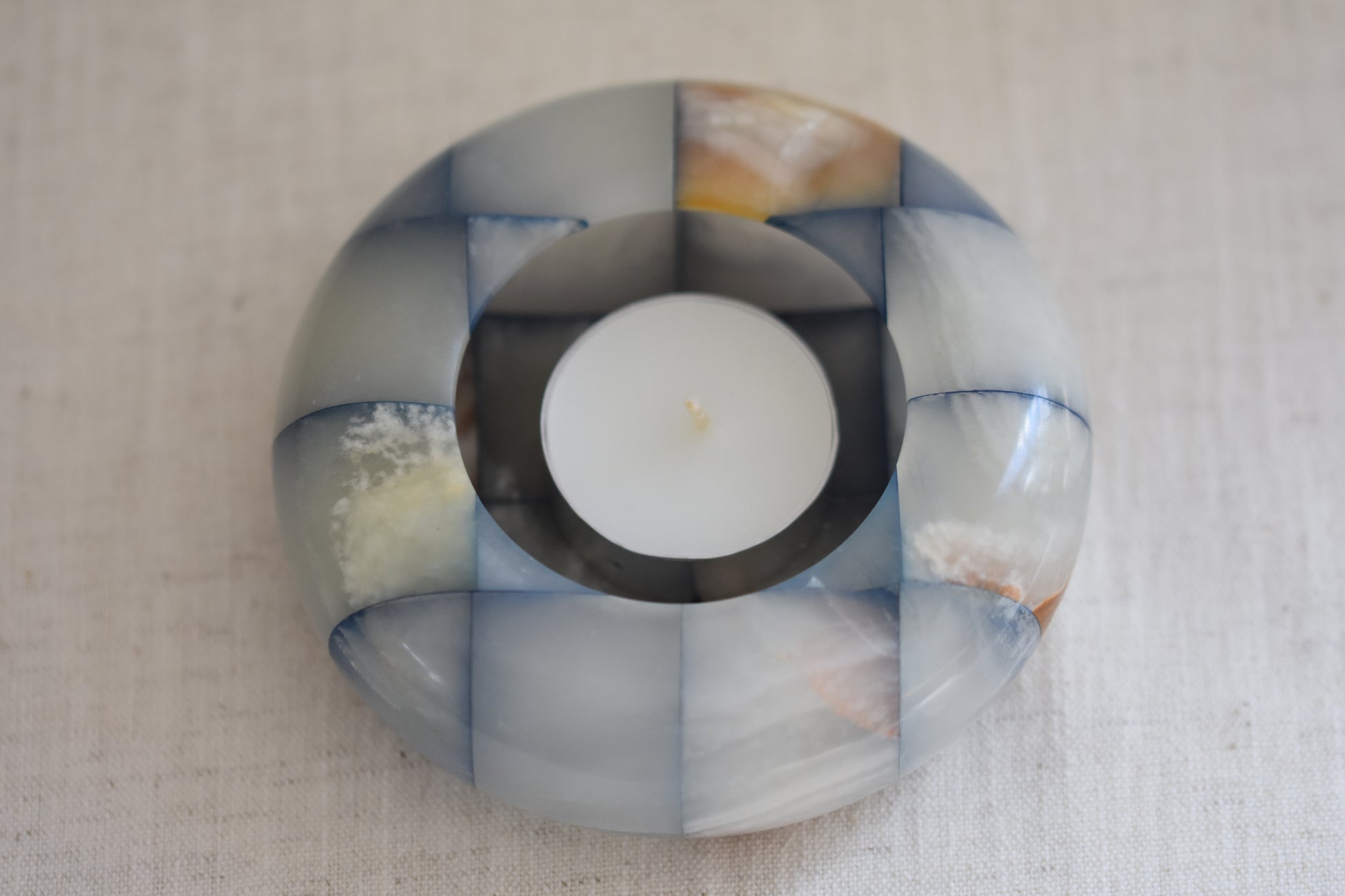 Vintage checkered onyx blue and brown tealight holder on a beige background.