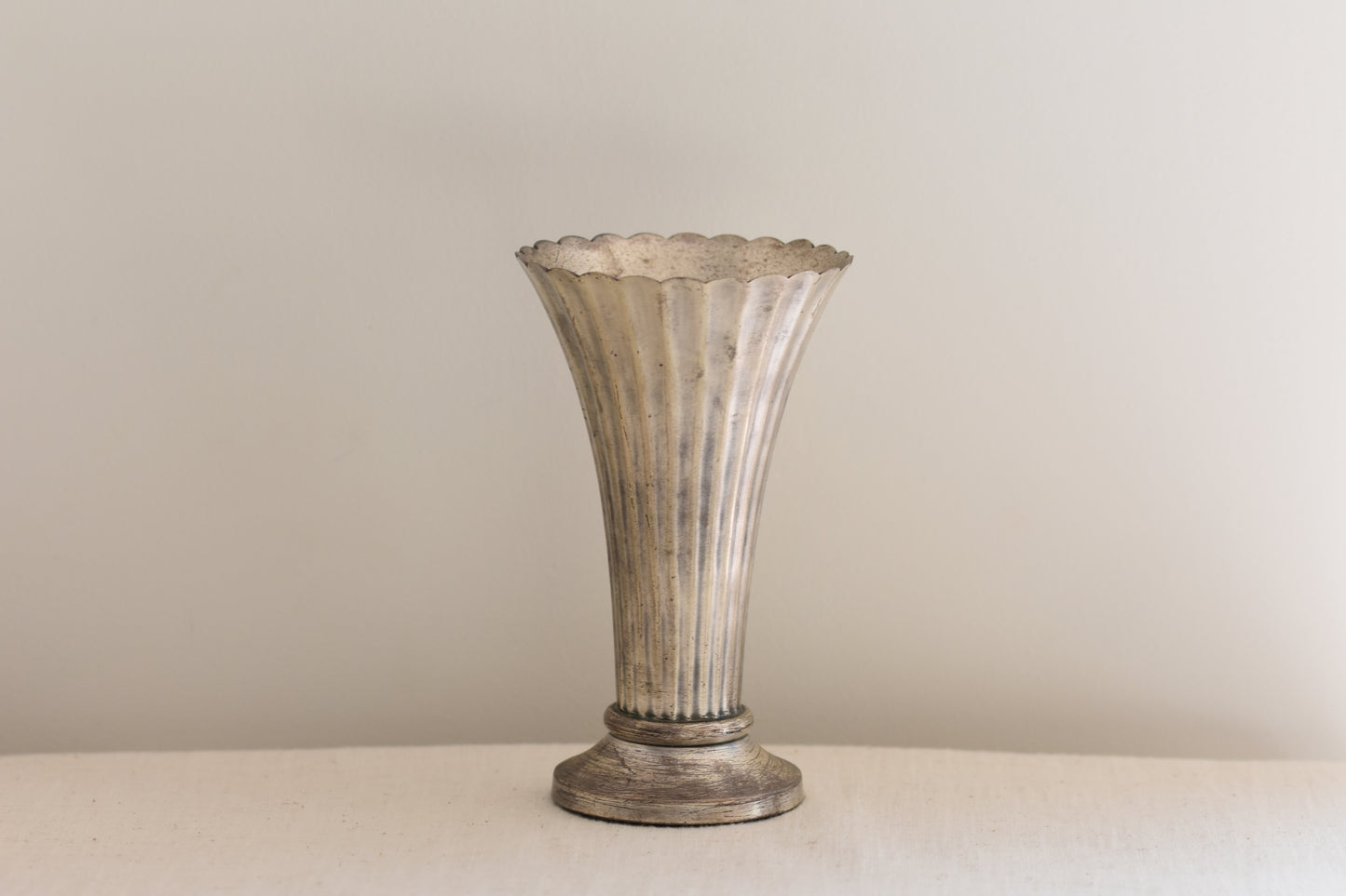 Vintage silver plated fluted vase on a beige background.