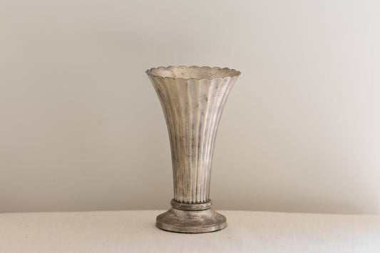 Vintage silver plated fluted vase on a beige background.