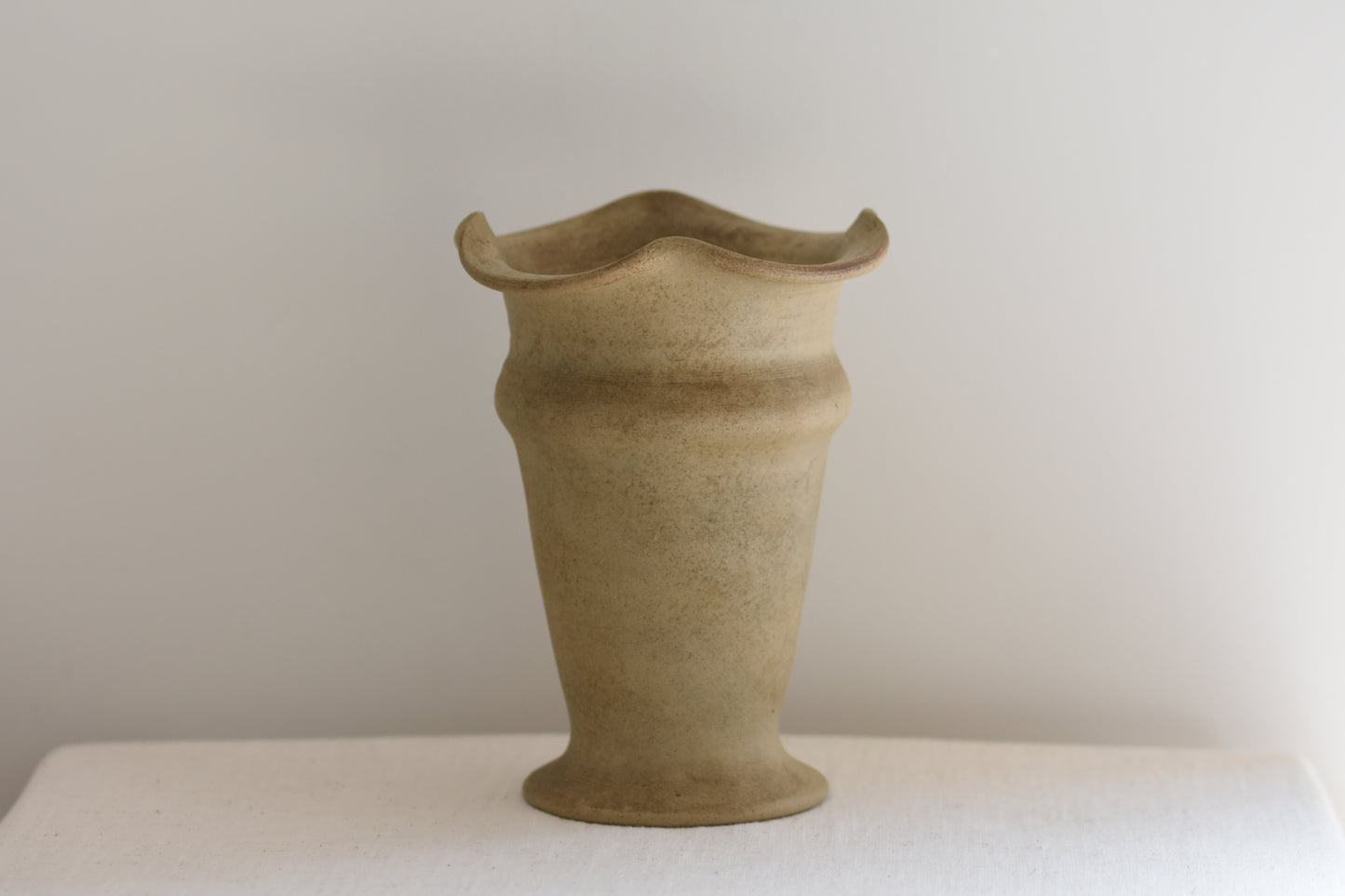 Vintage Hillstonia beige stoneware vase with wavy rim on a beige background.