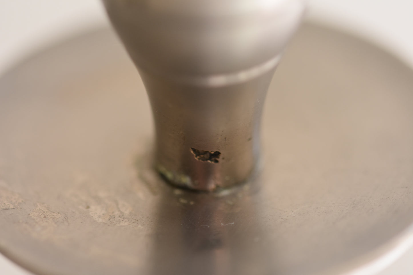 Close up of a vintage silver tone metal twist candlestick on a beige background.
