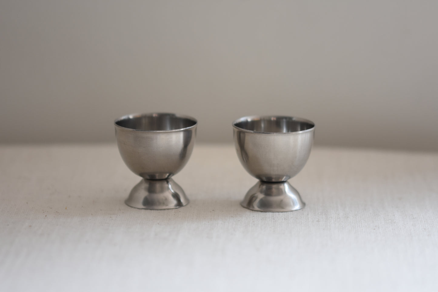 Pair of vintage Danish stainless steel egg cups on a beige background.