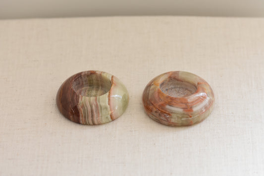 Pair of vintage green and brown onyx tealight holders on a beige background.