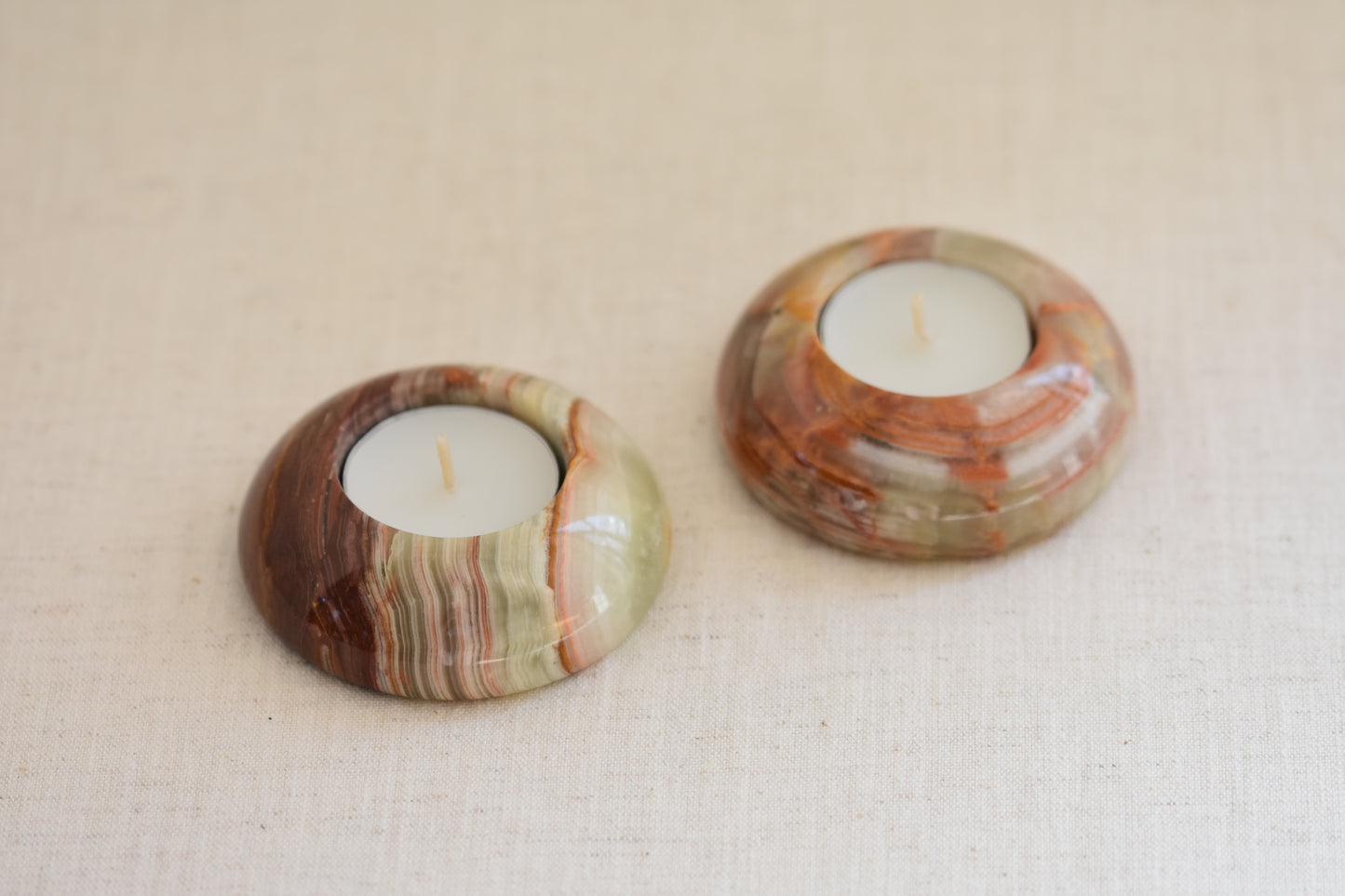 Pair of vintage green and brown onyx tealight holders on a beige background.
