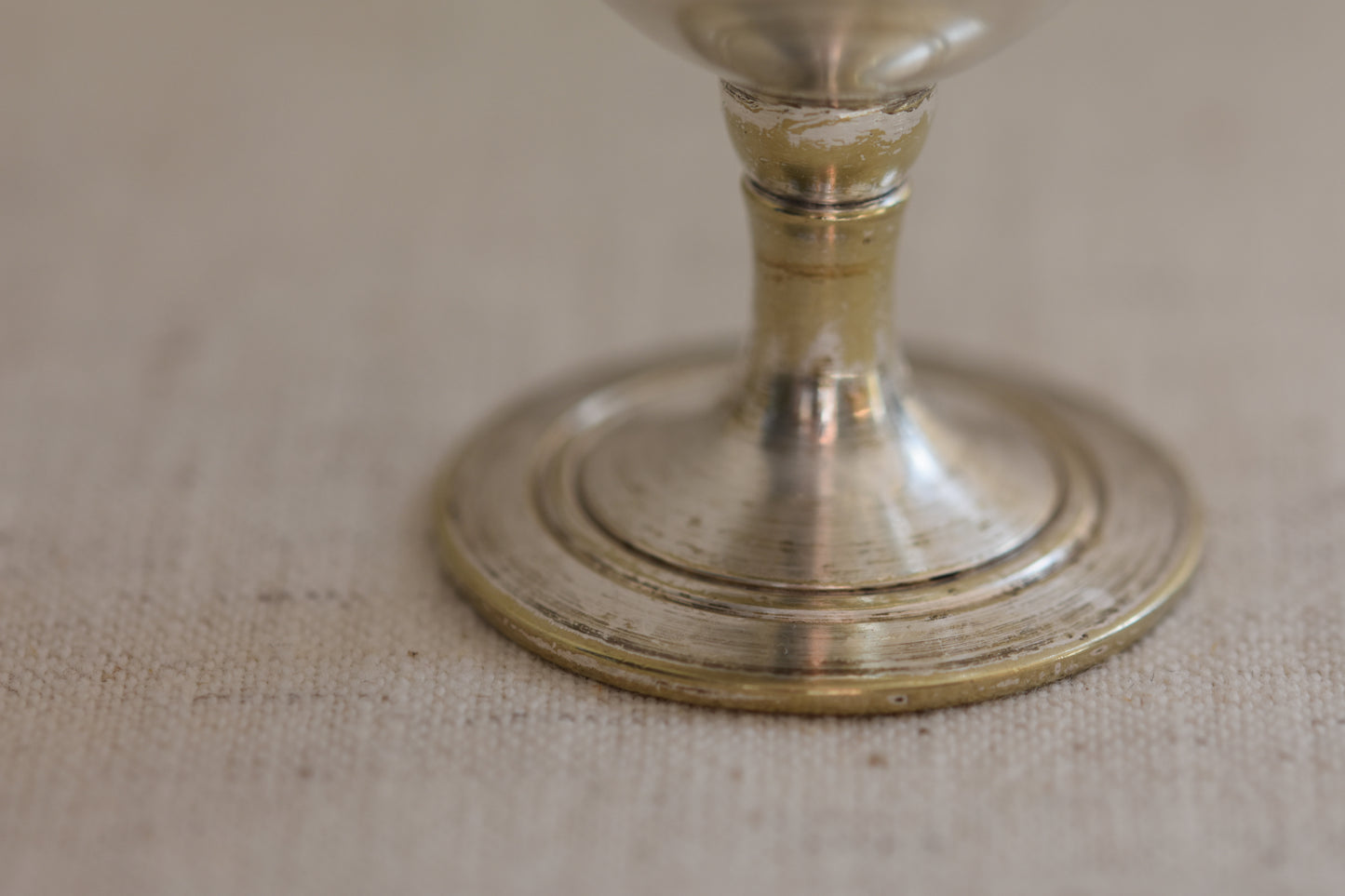 Close up of a vintage silver plated egg cup with crimped rim on a beige background.