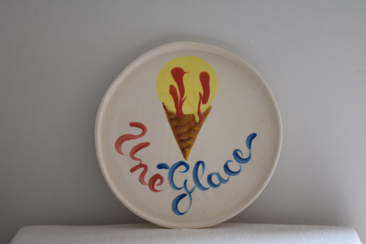 Le Crabe Une Glace ceramic plate with painted ice cream and French writing, on a beige background.