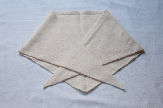Cream marl Merino wool triangle scarf by Roake Studio lay flat and crossed over on a beige background.