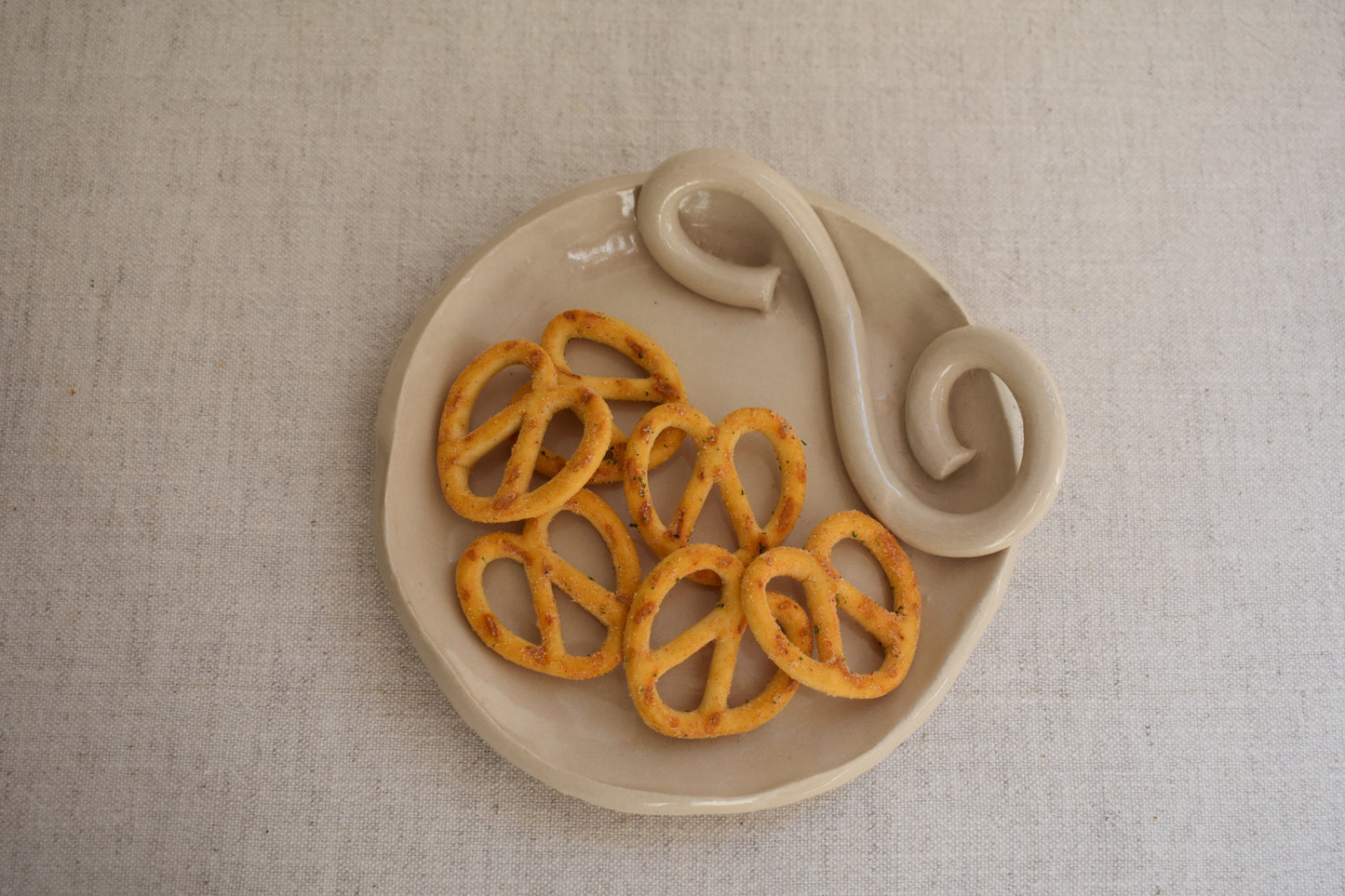 We Are Clay Wee Dish in white ceramic with spiral design holding pretzels.