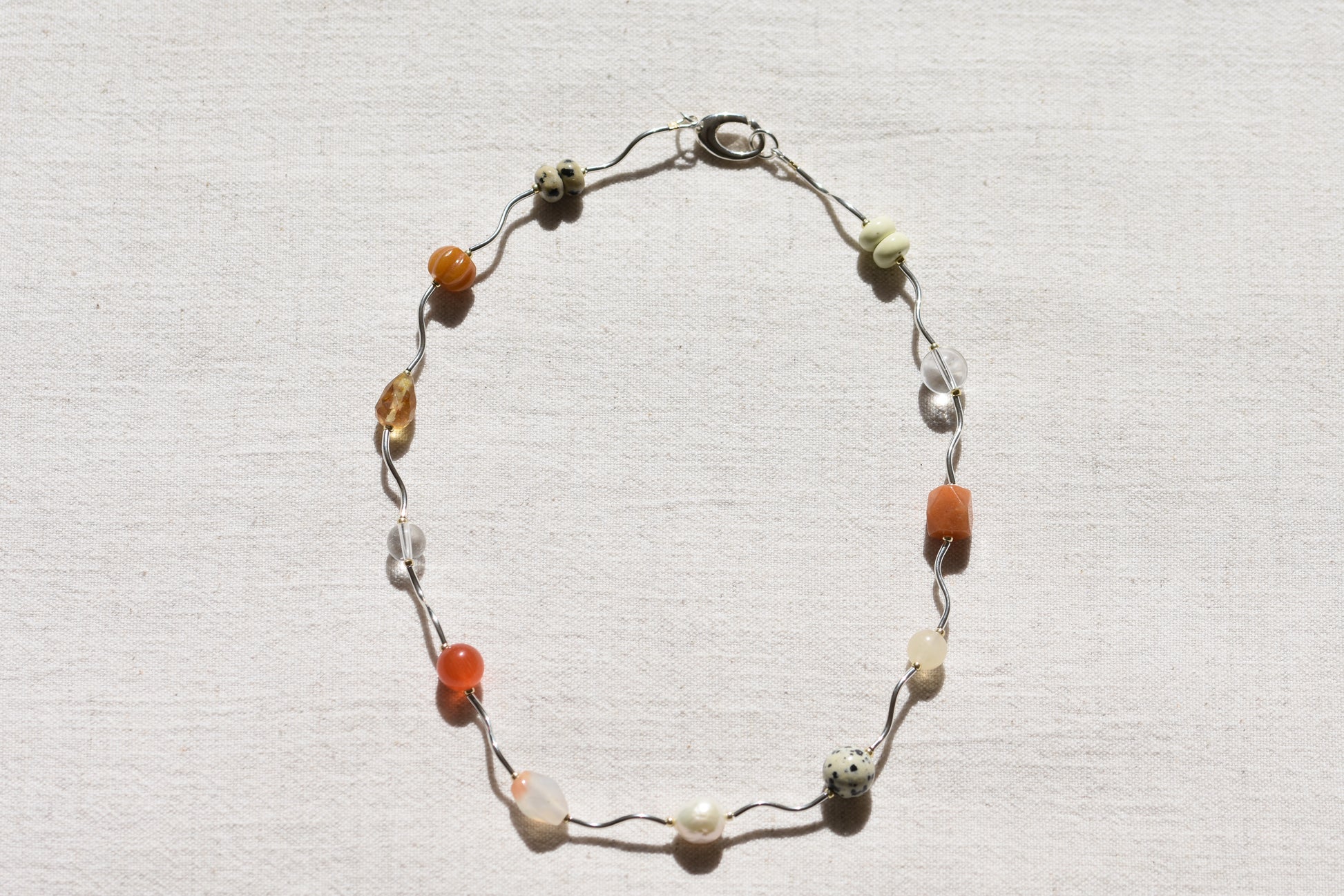 By my hands Sienna Ripple Necklace with wavy sterling silver ripples and oval clasp combined with earthy gemstones including unakite, dalmatian jasper, freshwater pearl, and coloured jade. 
