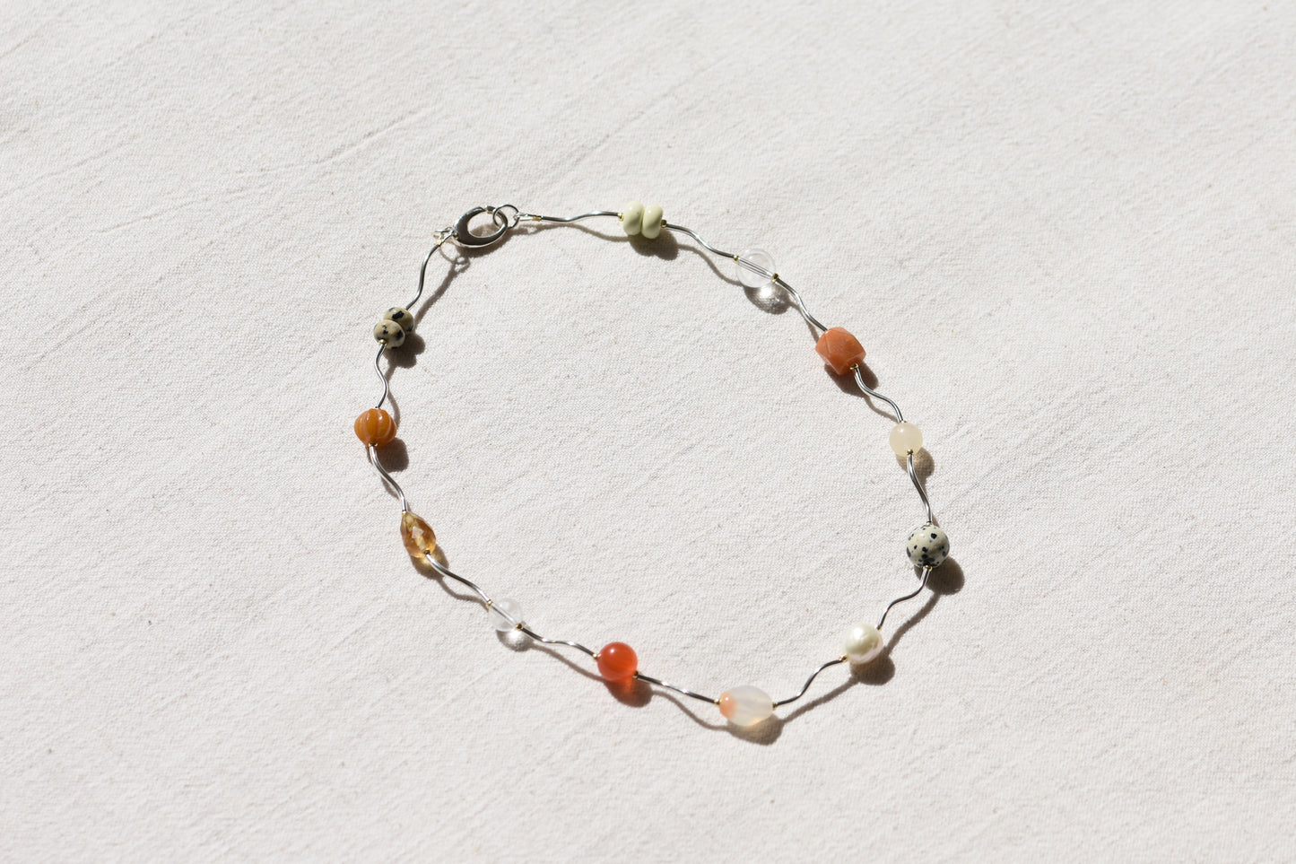 By my hands Sienna Ripple Necklace with wavy sterling silver ripples and oval clasp combined with earthy gemstones including unakite, dalmatian jasper, freshwater pearl, and coloured jade. 