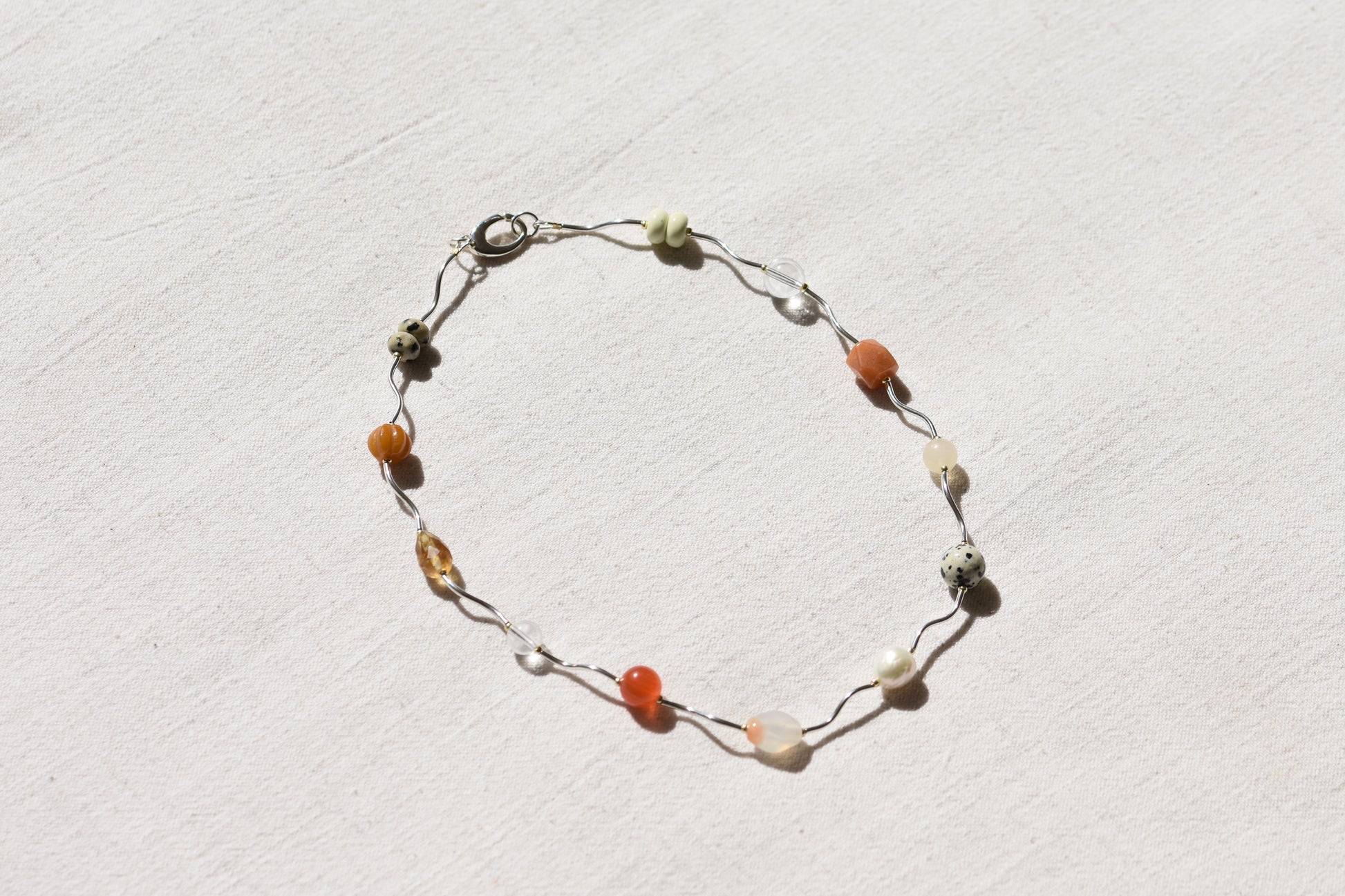By my hands Sienna Ripple Necklace with wavy sterling silver ripples and oval clasp combined with earthy gemstones including unakite, dalmatian jasper, freshwater pearl, and coloured jade. 