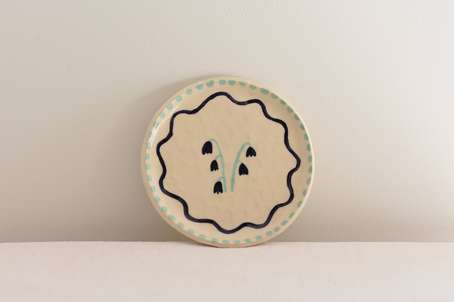 Blume Ceramics white stoneware small plate with hand painted floral design in navy and light green.