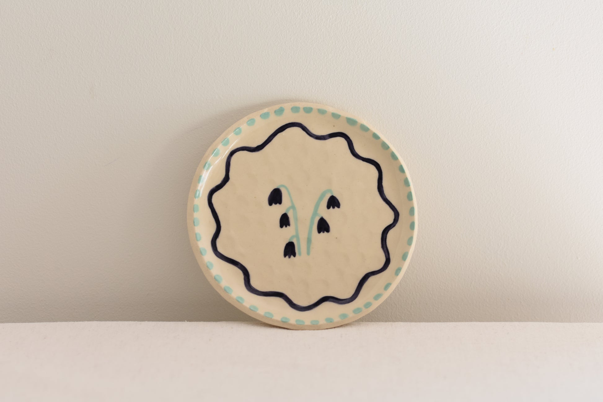 Blume Ceramics white stoneware small plate with hand painted floral design in navy and light green.