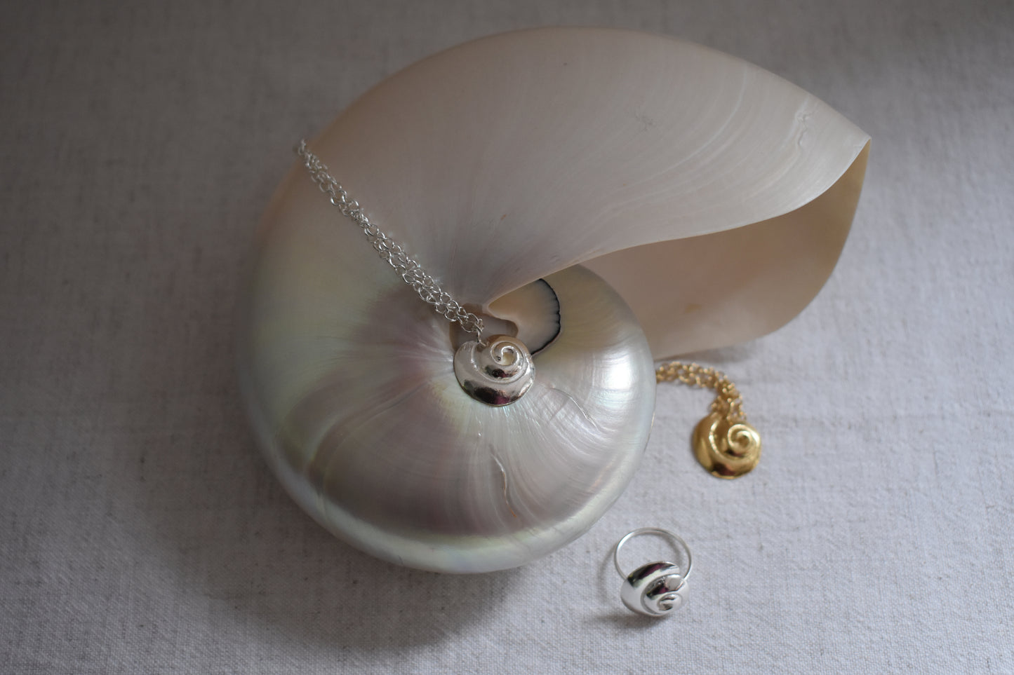 Hannah Bourn Periwinkle necklaces with spiral swirl shell pendant on a chain in gold and silver with Periwinkle ring in silver.