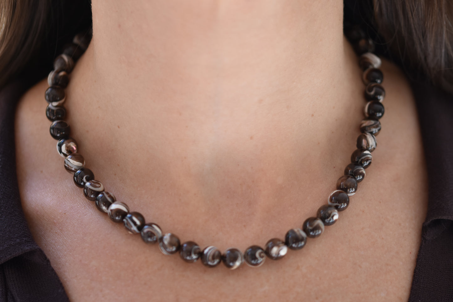 By my hands Burnt Umber Bei Necklace of opalescent dark brown Mother of Pearl beads, shown on a person.