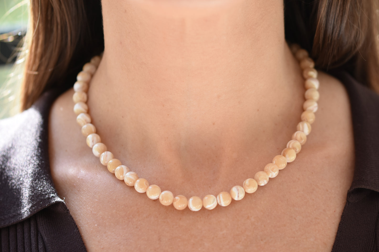 By my hands Sandy Bei Necklace of opalescent light yellow Mother of Pearl beads, shown on a person.