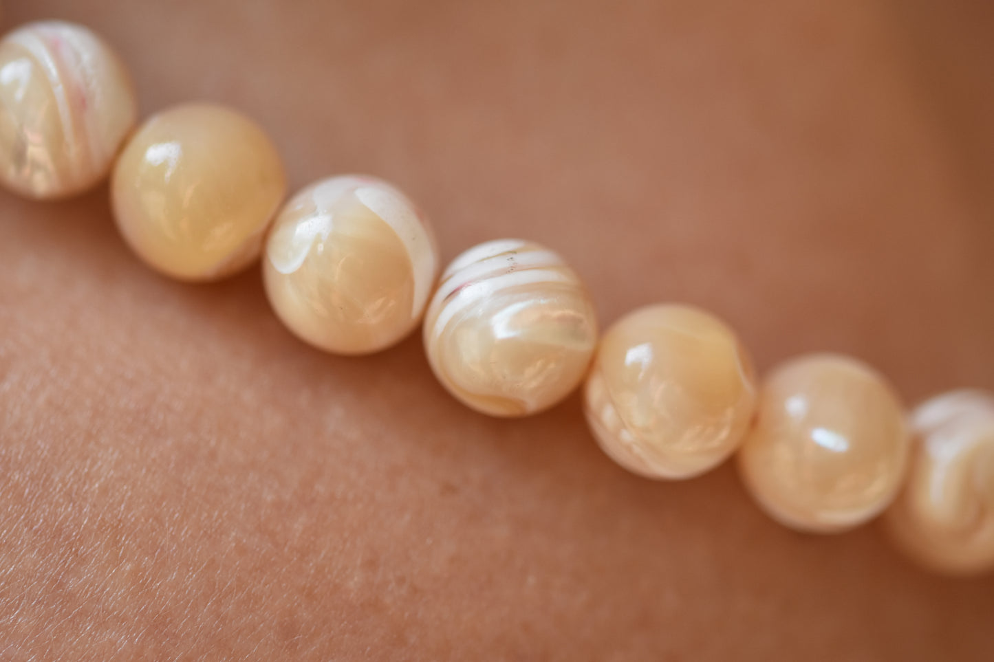 By my hands Sandy Bei Necklace of opalescent light yellow Mother of Pearl beads close up.