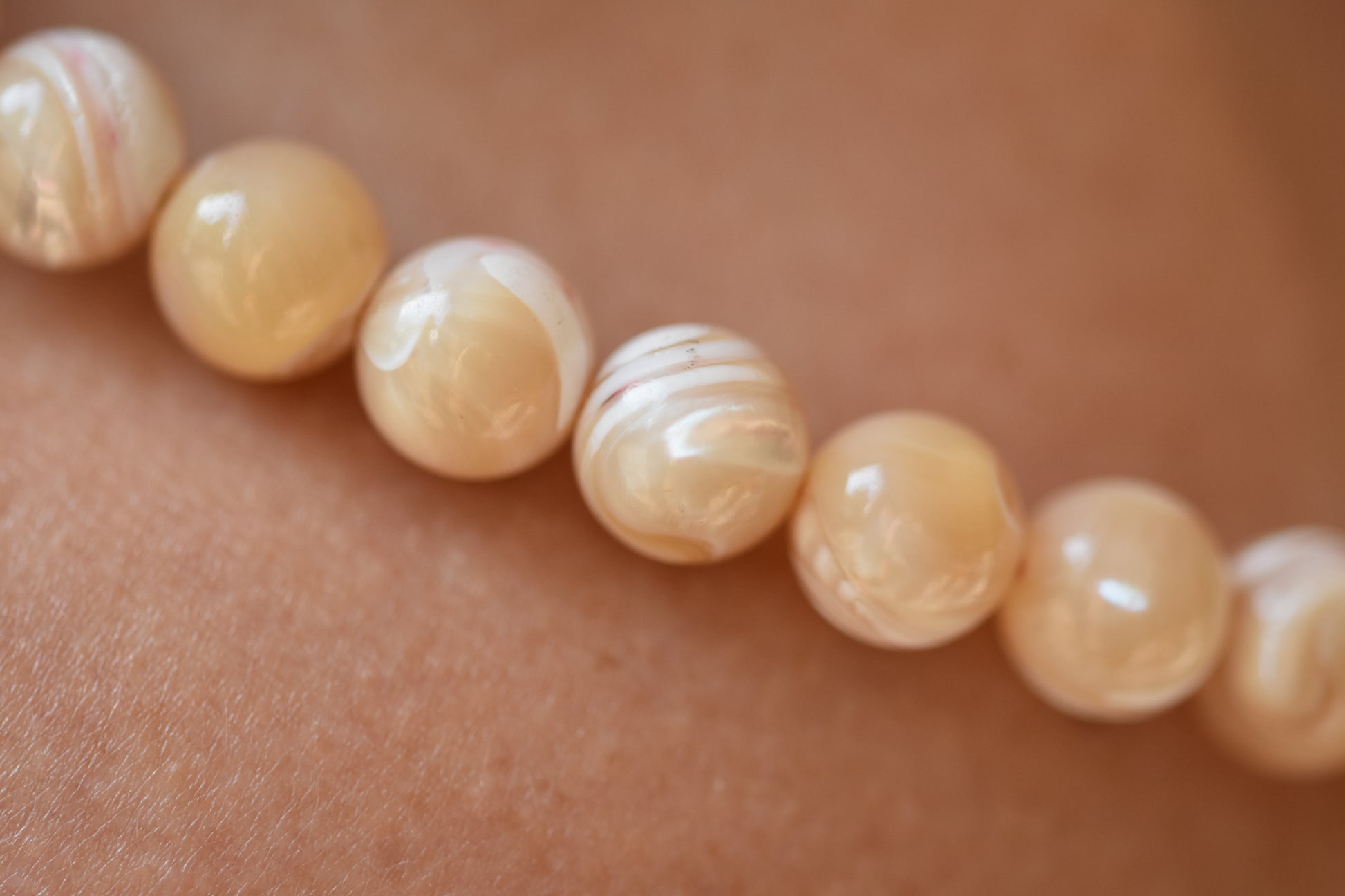By my hands Sandy Bei Necklace of opalescent light yellow Mother of Pearl beads close up.