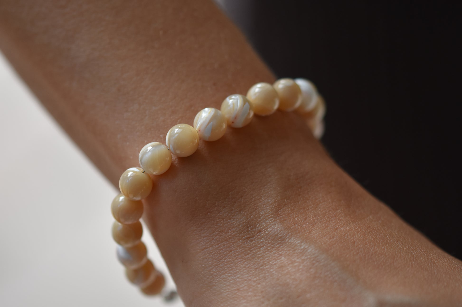 By my hands Sandy Bei Bracelet of opalescent light yellow Mother of Pearl beads, shown on a person.