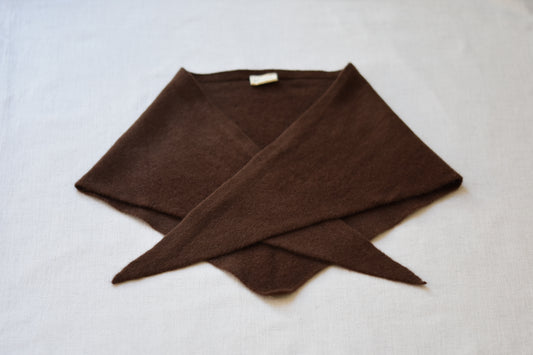 Roake Studio brown merino wool triangle scarf folded on a beige background.