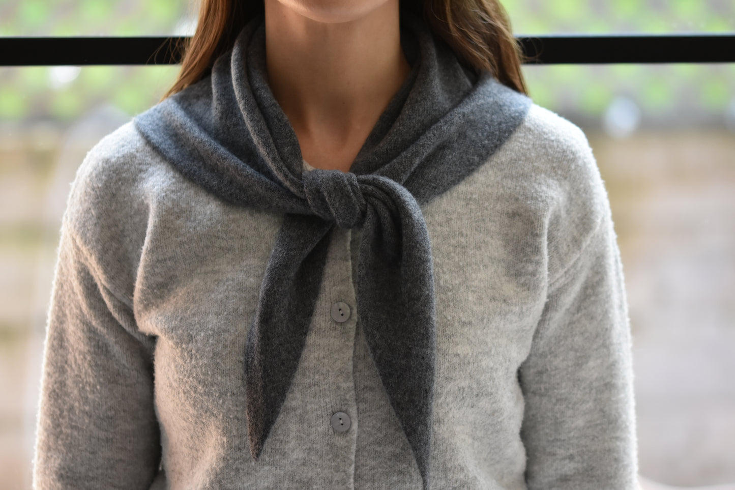Roake Studio grey merino wool triangle scarf with front knot, worn by a person in a grey cardigan.