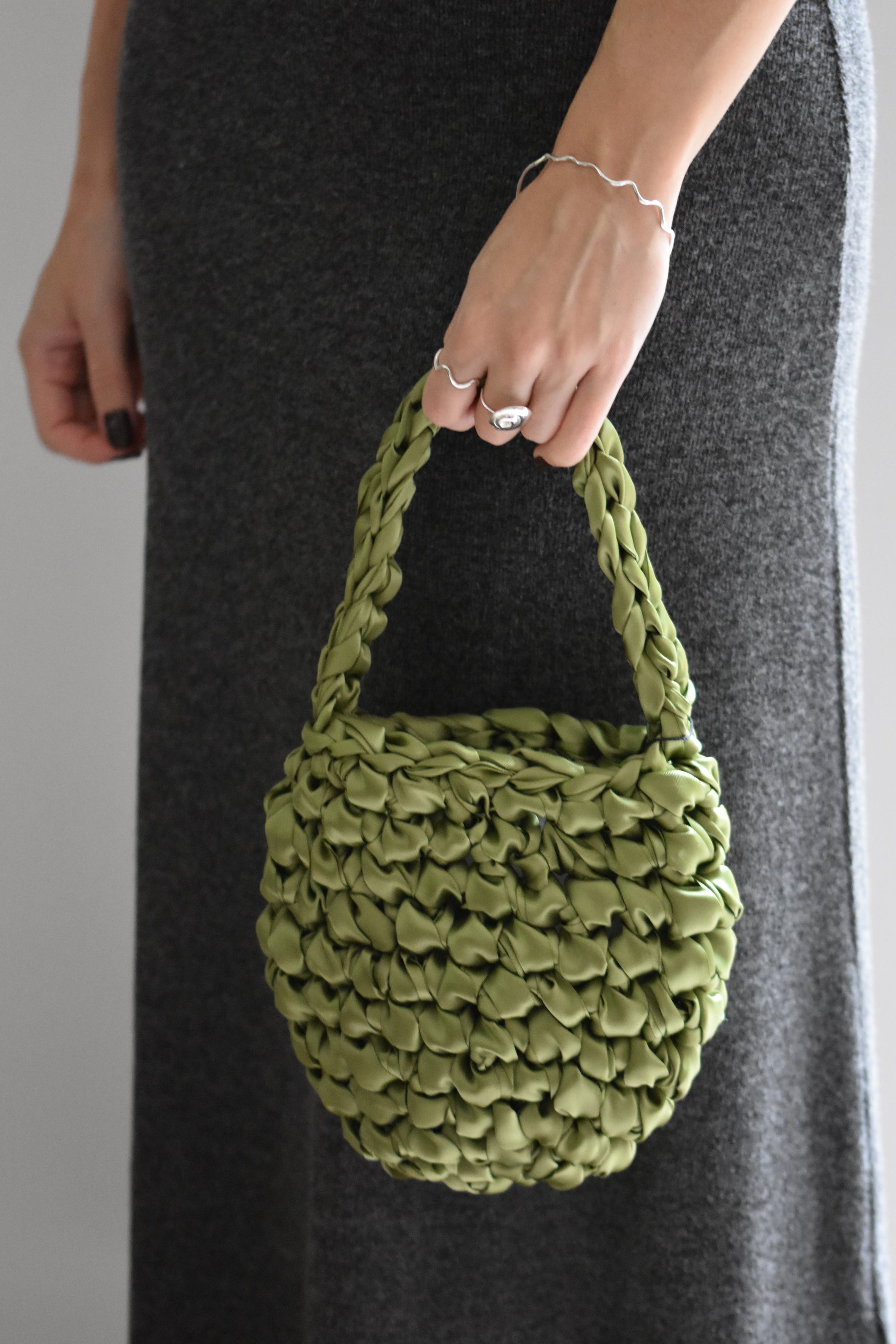 Isla de Gar Hive Bag with crocheted satin ribbon in spring moss green, shown with Hannah Bourn spiral Periwinkle ring in silver and wavy Saccostrea ring and bangle in silver.